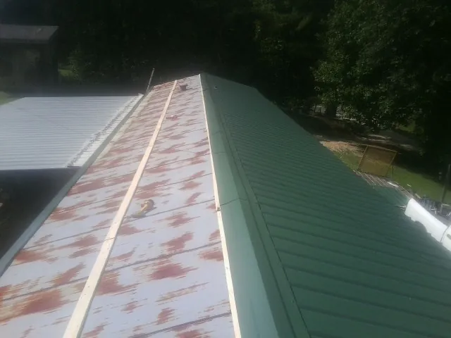 Old rusted panels beside newly installed green metal roofing — Wind Damage Roof Repair by Roofing Brothers in Broadview Heights