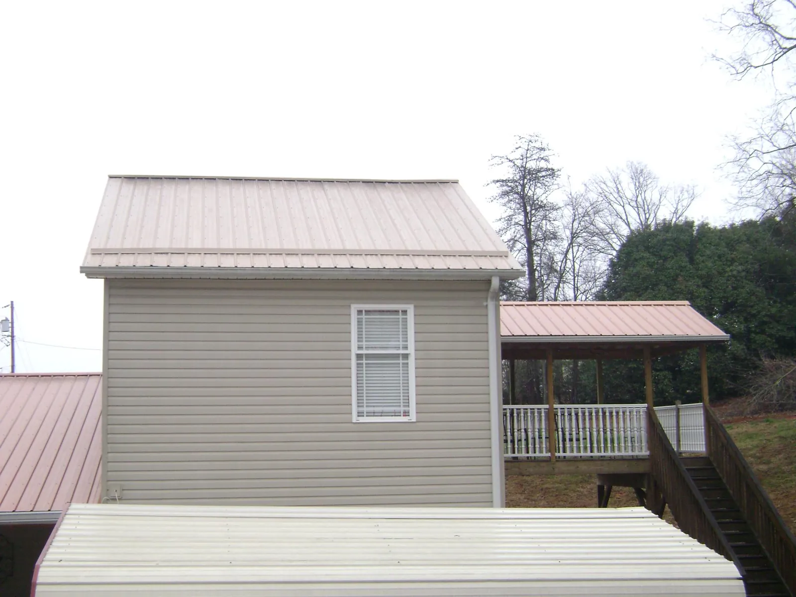 Tan metal roofs on a two story addition and attached porch, from a Roof Replacement job in Broadview Heights